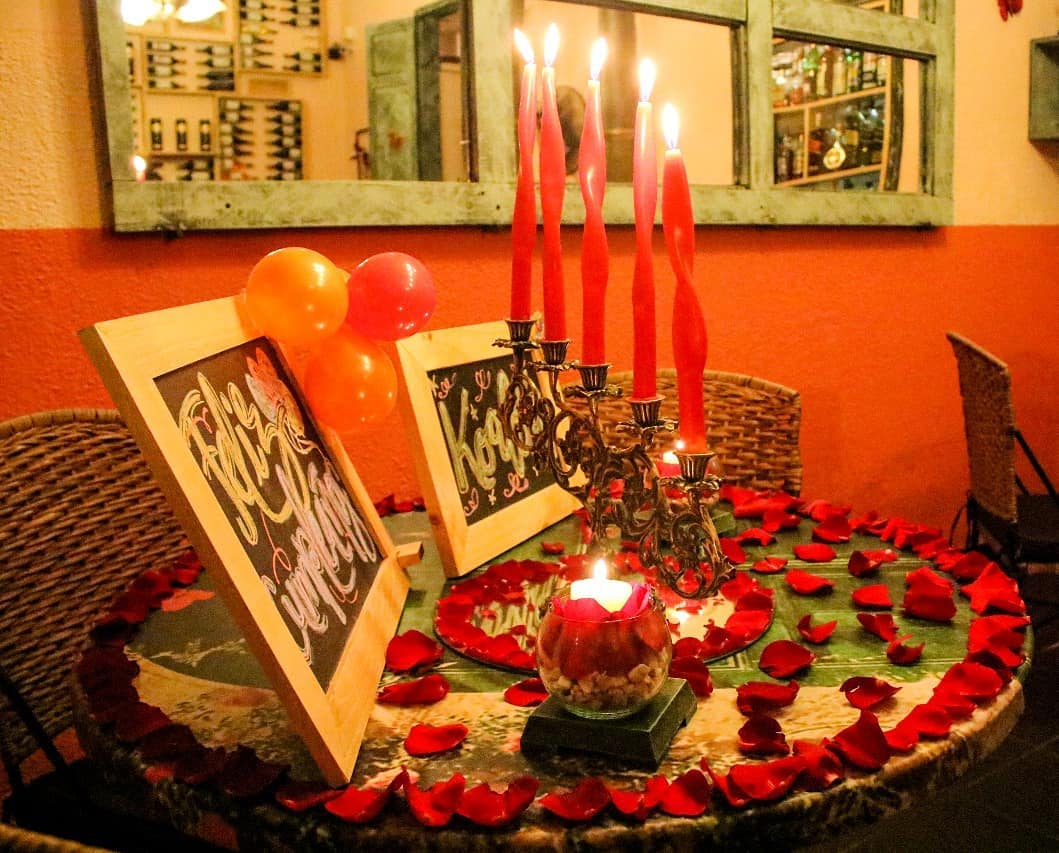 Mesa Romántica con Velas, Pétalos de Rosa y Dos Letreros Vintage Decorativos