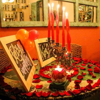 Mesa Romántica con Velas, Pétalos de Rosa y Dos Letreros Vintage Decorativos